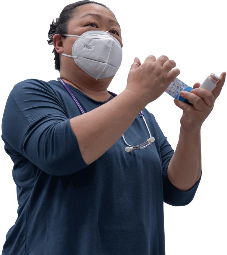 Joyce, Respiratory Therapist at BCCHC, is wearing a face mask and holding an inhaler.